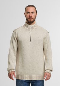 Strikket sweater i beige med høj krave, halv lynlås foran og ribbede manchetter. Har et tekstureret mønster med indslag af mørkere farver.
