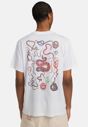 White cotton t-shirt with a graphic of various snakes on the back, featuring colors like red, black, and brown, alongside illustrative details.