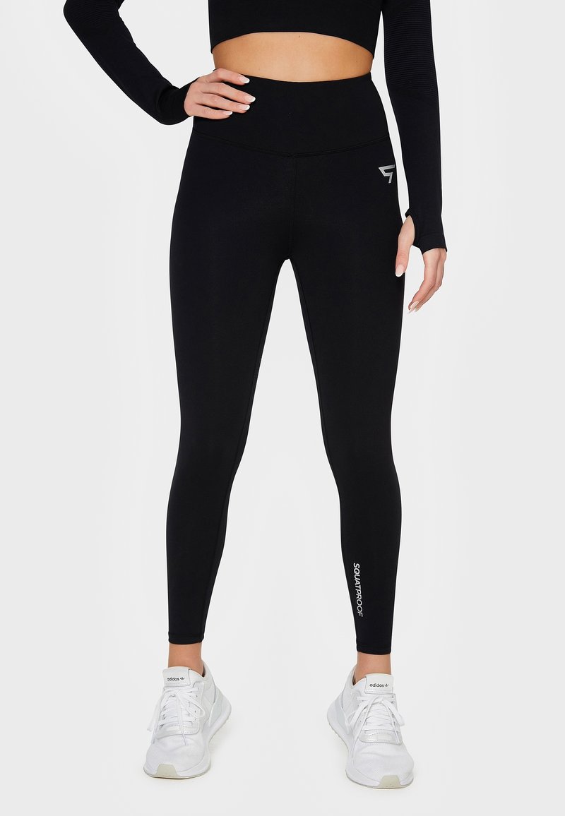 Czarne legginsy z wysokim stanem wykonane z elastycznego materiału o gładkiej fakturze. Posiadają białe logo "SQUATPROOF" przy kostce.