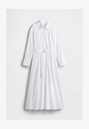 Biała bawełniana sukienka koszulowa z kołnierzykiem, długimi rękawami, paskiem w talii i kieszenią na piersi. Posiada zapięcie na guziki z przodu oraz rozkloszowany dół.