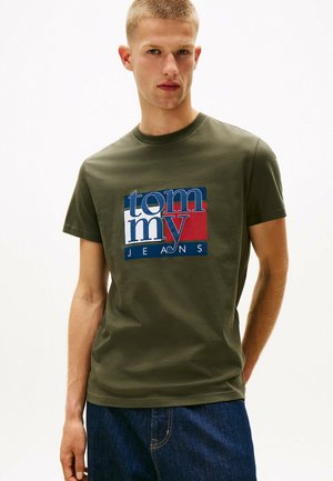 Oliven grøn bomulds t-shirt med et stort multicoloreret grafik med "tommy" og "JEANS" i fed typografi, rund halsudskæring og korte ærmer.