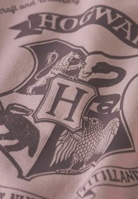 Tela con temática de Hogwarts que presenta un escudo burdeos con una prominente "H" blanca, adornado con un león, un águila y una serpiente en tonos apagados.