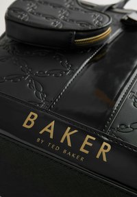 Borsa nera sintetica con motivo in rilievo, testo dorato "BAKER by TED BAKER," dotata di una pochette removibile e chiusura a zip.