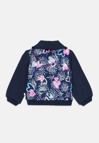 Felpa blu navy con un retro decorato da paillettes, che presenta fenicotteri colorati e forme astratte. Polsini e colletto a costine.