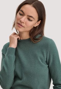 Mintgrüner Pullover mit Rundhalsausschnitt, gerippten Bündchen und einer weichen Textur. Der Stoff wirkt leicht und glatt, ideal zum Schichten.