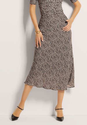 Leopardenmuster Midi-Rock aus leichtem Stoff, mit einer fließenden Silhouette und einem Saum, der sanft ausgestellt ist. Schwarze spitze Schuhe.