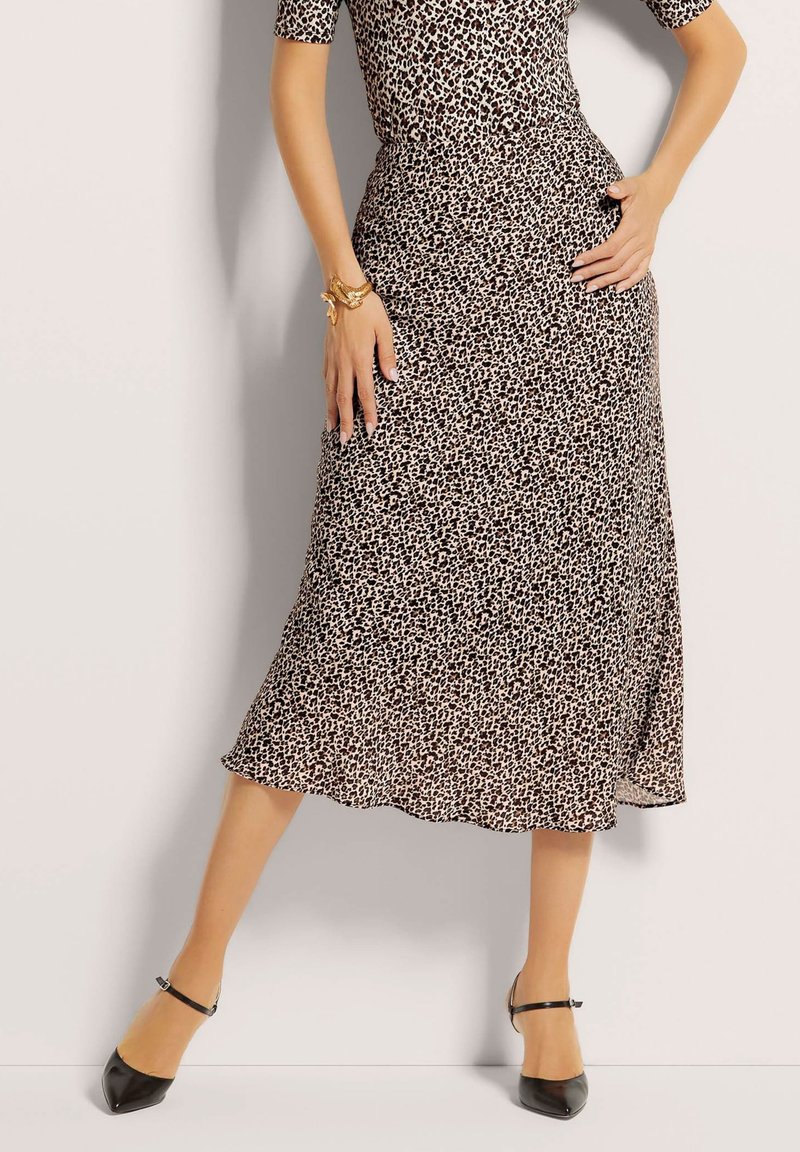 Leopardenmuster Midi-Rock aus leichtem Stoff, mit einer fließenden Silhouette und einem Saum, der sanft ausgestellt ist. Schwarze spitze Schuhe.