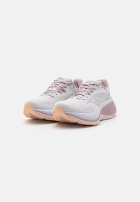 Baskets de sport blanches avec des accents rose clair, tige en maille, semelle rembourrée et semelle en caoutchouc texturée. Marquage prominent sur les côtés.