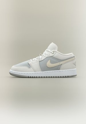 Baskets basses Nike Air Jordan gris clair et blanc avec fermeture à lacets et semelle texturée sur fond uni.