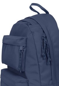 Marineblaue Tasche aus strukturiertem Nylonmaterial, mit doppeltem Reißverschluss, einer Fronttasche und einem oberen Griff zum Tragen. Verstellbare Kordeln sind sichtbar.