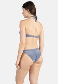 Bikini bleu pailleté, design à col montant, attache réglable à l'arrière, bas taille basse, texture lisse, et détails matériels minimaux.