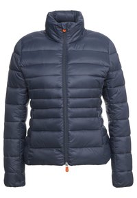 Veste matelassée bleu marine avec un col montant, design matelassé, fermeture éclair avant et tirette de fermeture éclair orange. Texture lisse et brillante, sans motifs visibles.