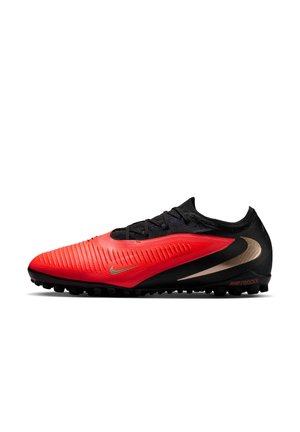 Niskie buty sportowe z czerwono-czarną cholewką, złotym logo Nike i czarną teksturowaną podeszwą, zaprojektowane na nawierzchnie sztuczną lub trawiastą.