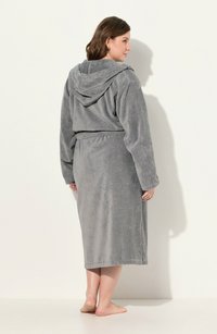 Accappatoio grigio con cappuccio realizzato in un morbido tessuto testurizzato. Presenta una vita con cintura e un design lungo, con maniche lunghe e dettagli minimi.