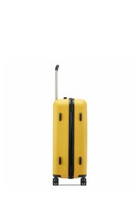 Maleta rígida amarilla con acentos negros, diseño vertical, asa extensible, cuatro ruedas y asas laterales para un fácil manejo.