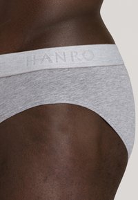 Slip in cotone grigio con una fascia in grigio chiaro caratterizzata dal logo "HANRO" in rilievo. Texture liscia e design aderente.