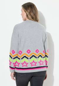 Grå stickad tröja med klara rosa, orange, gröna och svarta geometriska mönster vid nederkant och ärmar. Ribbade mudd och nederkant.