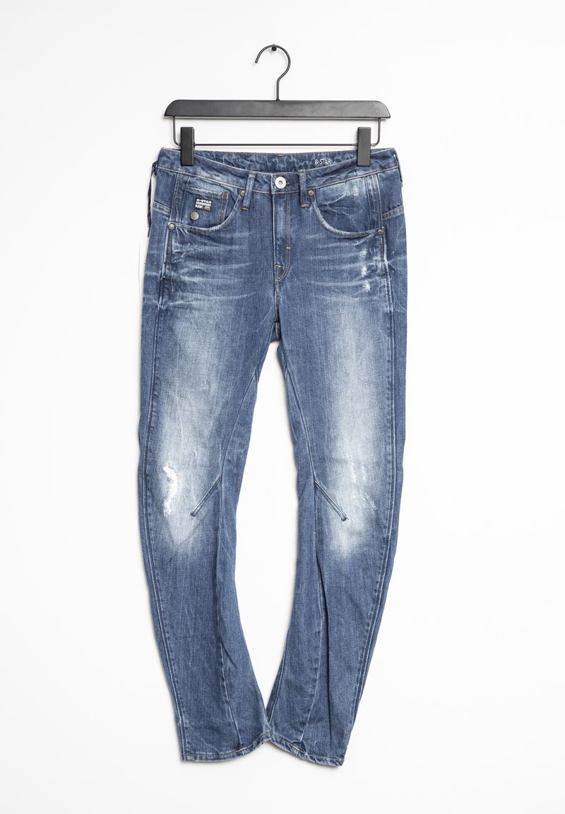 Blå denimjeans med en urtvättad finish och slitna detaljer. Inkluderar fickor och en knäppning. Hänger från en svart krok.