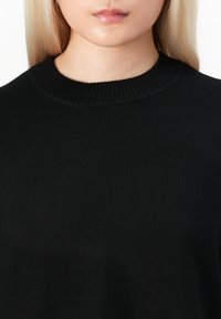 Svart strikket genser med ribbestrikket crew hals, med en jevn tekstur og minimalistisk design, egnet for hverdagsbruk.