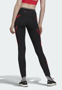 Czarne legginsy z czerwonymi akcentami po bokach, wysoki stan i wygodny materiał. Posiadają zamek błyskawiczny z tyłu oraz przeszywane logo w pasie.