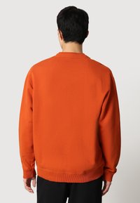 Sudadera naranja de cuello redondo con puños y dobladillo acanalados, que presenta una tela suave y texturada. La vista trasera muestra un ajuste relajado y un diseño sencillo.