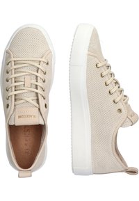 Baskets beiges à lacets avec une texture perforée, semelles en caoutchouc blanches, œillets métalliques et une petite étiquette logo sur le talon.