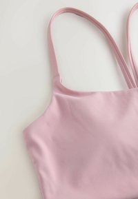 Hele roosa varrukateta top, millel on sile tekstuur, õhukesed rihmad ja kõver kaelus. Lihtne disain ilma lisamustriteta.