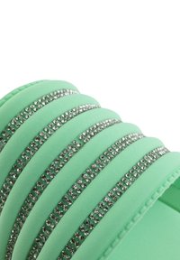 Sandal in verde menta con fascia a strati decorata con strass trasparenti. Texture morbida con finitura liscia e bordi arrotondati.