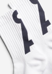 Weiße Sportsocken mit gerippter Textur und einer dunkelblauen Zahlengrafik. Das Design umfasst eine verstärkte Ferse und Spitze für Haltbarkeit.