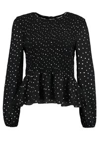 Black blouse with long sleeves featuring a smocked bodice and peplum hem. Decorated with small white polka dots and a round neckline.