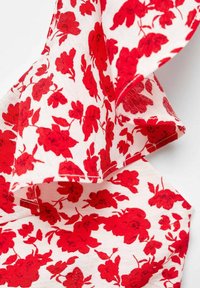 Květnatý látkový vzor má bílý podklad s živými červenými květinami, které se vyznačují různými velikostmi a tvary. Jemná textura, lehký materiál.