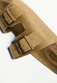 Barna suede thong szandál, két állítható fémbuckles-szel és texturált talppal, vastag, bordázott talppal.