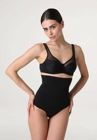 Set di lingerie nero composto da un reggiseno trasparente con stecche e mutandine alte modellanti, entrambe in tessuto morbido, che mettono in risalto una silhouette snella.