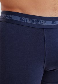 Marineblaue Boxershorts aus weichem Stoff, mit einem gewebten elastischen Bund, der mit "JBS UNDERWEAR"-Branding versehen ist. Glatte Textur, enganliegendes Design.