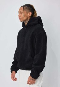 Polaire noire à col montant avec poches. Texture douce, coupe décontractée. Manches longues avec poignets côtelés.