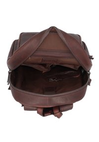 Sac à dos en cuir marron avec une finition texturée. L'intérieur comprend une poche zippée et un clip, avec un revêtement lisse marron. Ouvert par le haut.