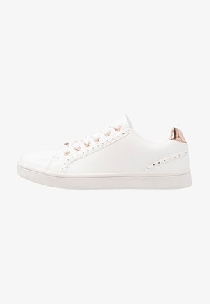 Vit sneakers med en slät syntetisk ovandel, metallhål och en roséguldaccent på hälen. Har dekorativ sömmar och perforeringar.