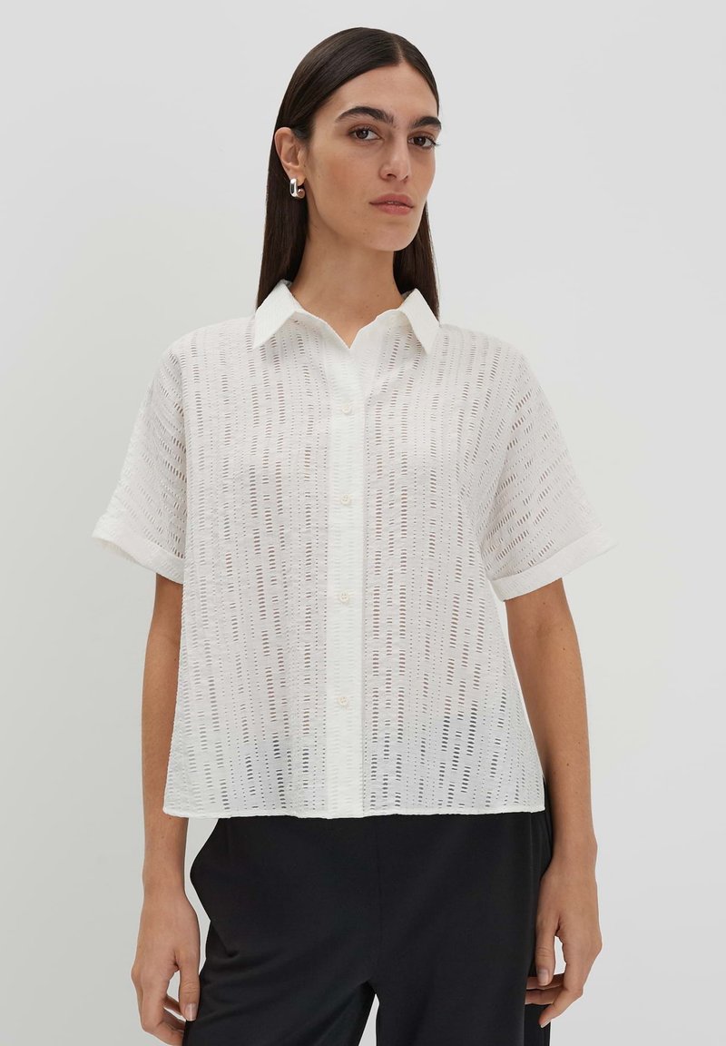 Camicia bianca a maniche corte con colletto button-down, tessuto testurizzato con motivi verticali a taglio e vestibilità comoda.