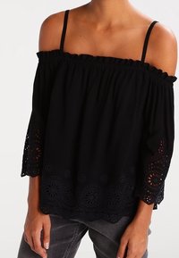 Top nero off-shoulder con scollatura arricciata e maniche a tre quarti. Presenta dettagli in pizzo intricati lungo le maniche e l'orlo.