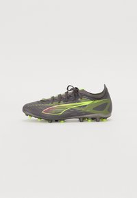Fotballsko med grå mesh-overdel, neon grønne detaljer og et strømlinjeformet design. Har fremtredende tekstur og pigg såle for grep.