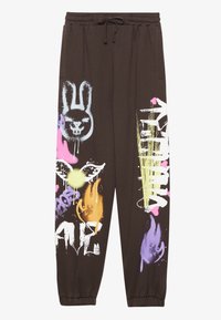 Bruna sweatpants med dragsko i midjan, elastiska muddar och färgglada graffiti-inspirerade tryck, inklusive en kanin, eldflammor och textaccenter.