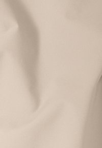 Tissu beige lisse avec des plis doux et une texture subtile, éclairé uniformément, montrant des ombres douces et des reflets.