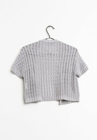 Harmaa, lyhythihainen neulecardigan, jossa on aaltoilu kuvio, löysällä istuvuudella ja avoimella etuosalla, roikkumassa mustassa koukussa.