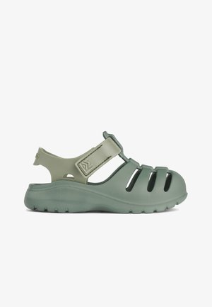 Chanclas verdes de plástico moldeado con un diseño abierto, que presentan acentos en las correas, lados texturizados y recortes huecos para ventilación.