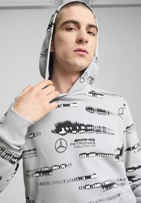 Gray hoodie featuring black abstract patterns and logos, long sleeves with ribbed cuffs, and a drawstring hood.