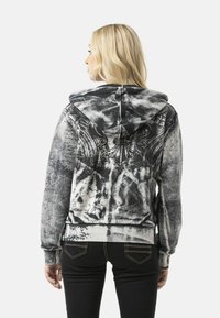 Hooded sweatshirt in black and white with abstract patterns and text prints; soft fabric, regular fit, ribbed cuffs, and hem.