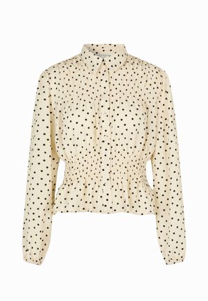 Krämfärgad blus med svarta prickar, långa ärmar, knappstängning fram och smockdetalj i midjan. Mjuk tygkvalitet med en avslappnad passform.
