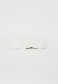 Semelle de sneaker en caoutchouc blanc avec motif de grip texturé, présentant des motifs de semelle définis et une zone de bout arrondie. Design minimaliste, profil plat.