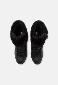 Baskets montantes noires avec une bordure en fausse fourrure, cuir texturé, design à lacets et fermeture éclair sur le côté pour un enfilage facile.