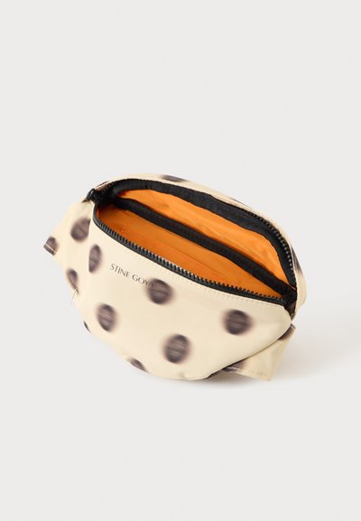 Pochette zippée beige et noire à pois avec doublure intérieure orange vif et "STINE GOYA" imprimé sur le devant.